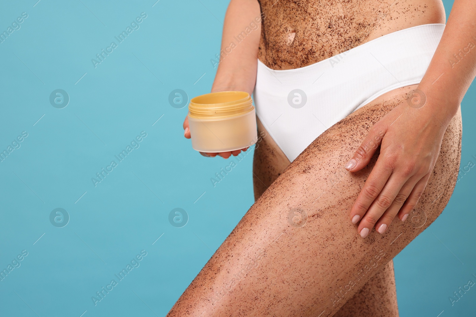 Woman with body scrub on her skin and jar against light blue background, closeup. Space for text Photo of Woman with body scrub on her skin and jar against light blue background, closeup. Space for text