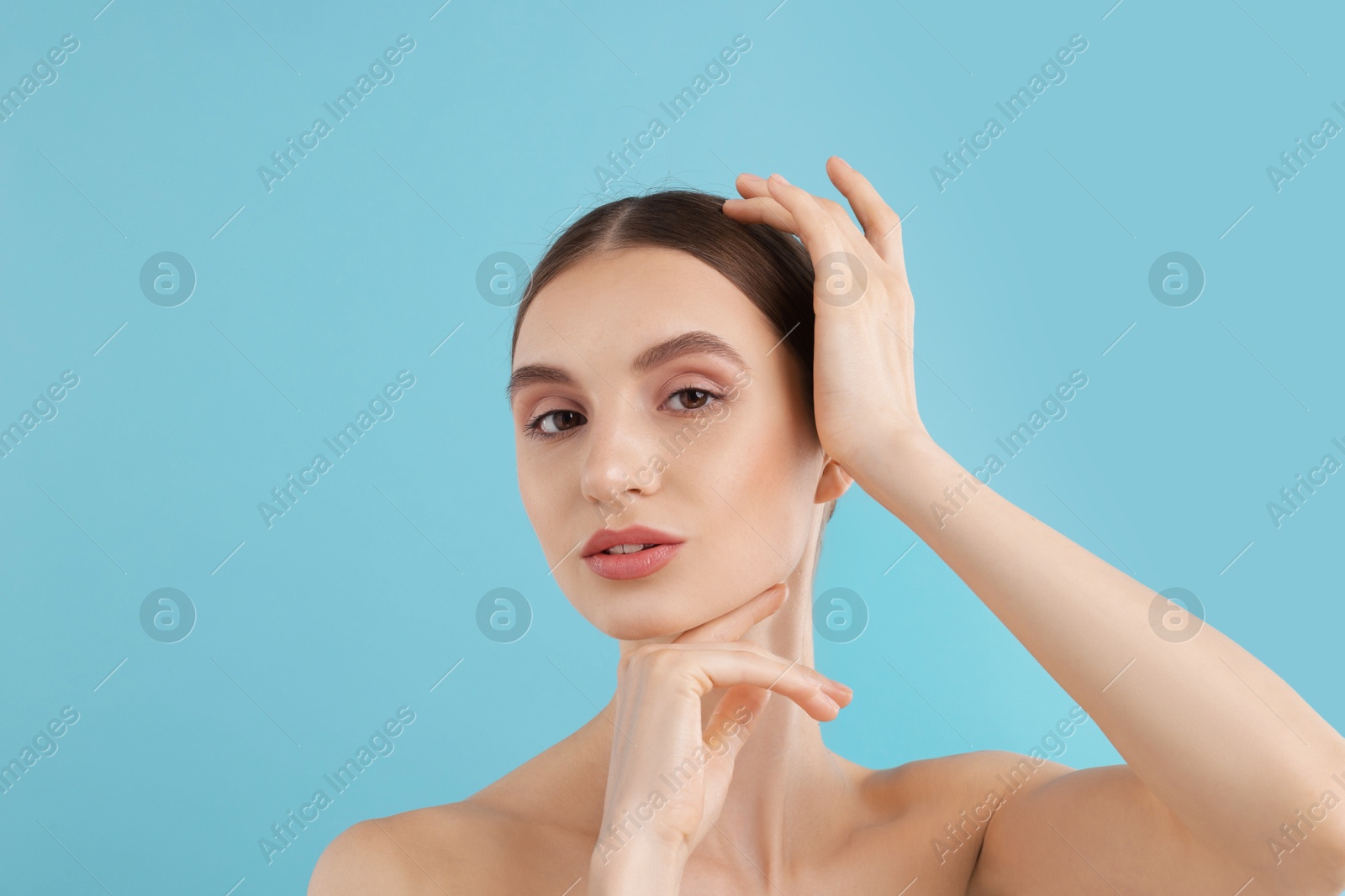 Portrait of charming young woman on light blue background Photo of Portrait of charming young woman on light blue background