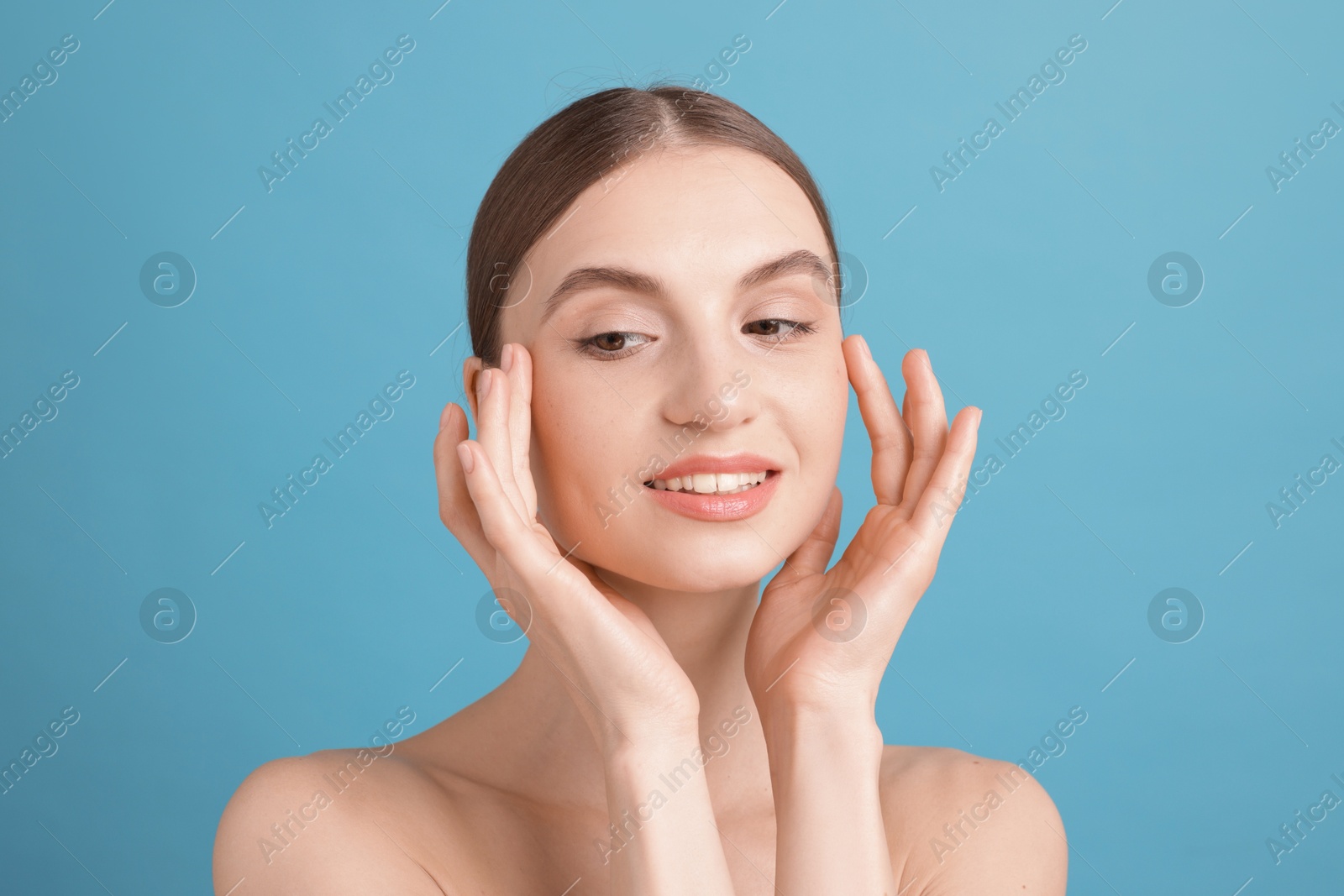 Portrait of charming young woman on light blue background Photo of Portrait of charming young woman on light blue background