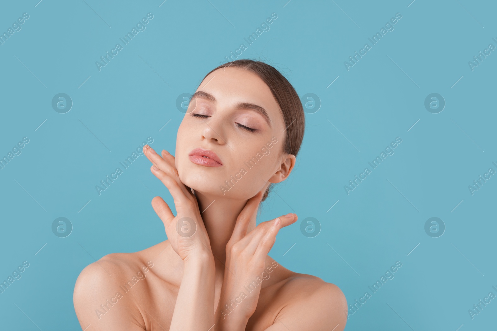 Portrait of charming young woman on light blue background Photo of Portrait of charming young woman on light blue background