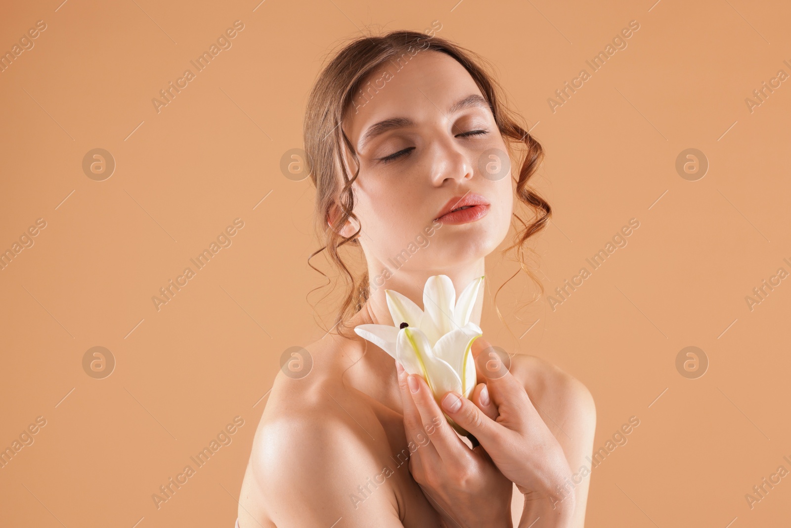 Portrait of beautiful young woman with flower on beige background Photo of Portrait of beautiful young woman with flower on beige background