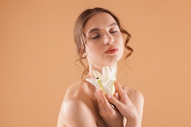 Photo of Portrait of beautiful young woman with flower on beige background