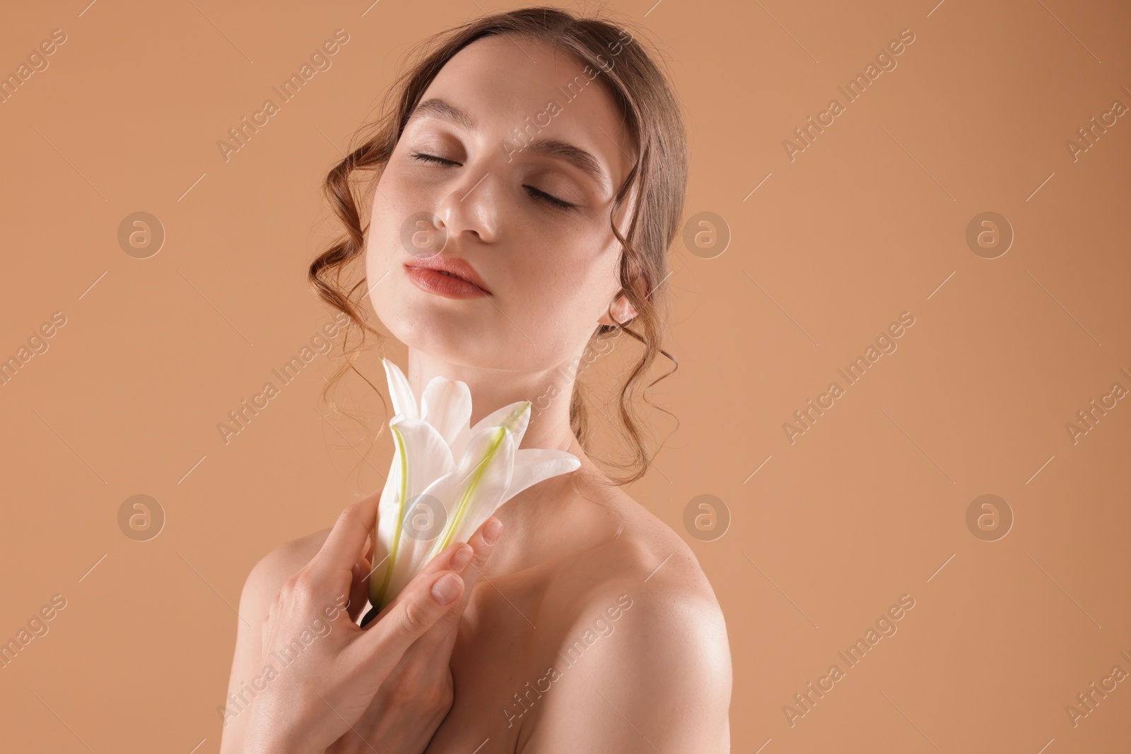 Portrait of beautiful young woman with flower on beige background Photo of Portrait of beautiful young woman with flower on beige background