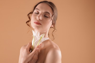 Photo of Portrait of beautiful young woman with flower on beige background