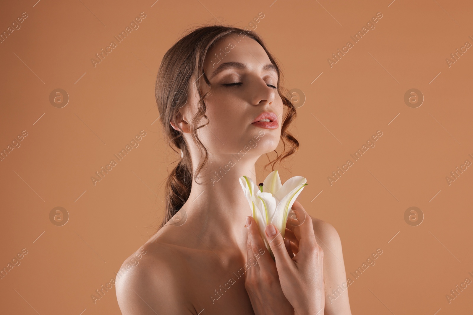 Portrait of beautiful young woman with flower on beige background Photo of Portrait of beautiful young woman with flower on beige background