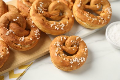 Photo of Tasty pretzels with salt on white marble table, above view