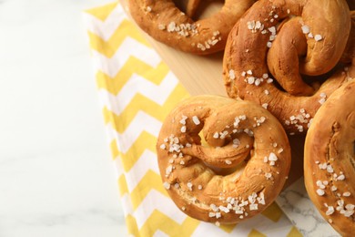 Photo of Tasty pretzels with salt on white table, above view. Space for text