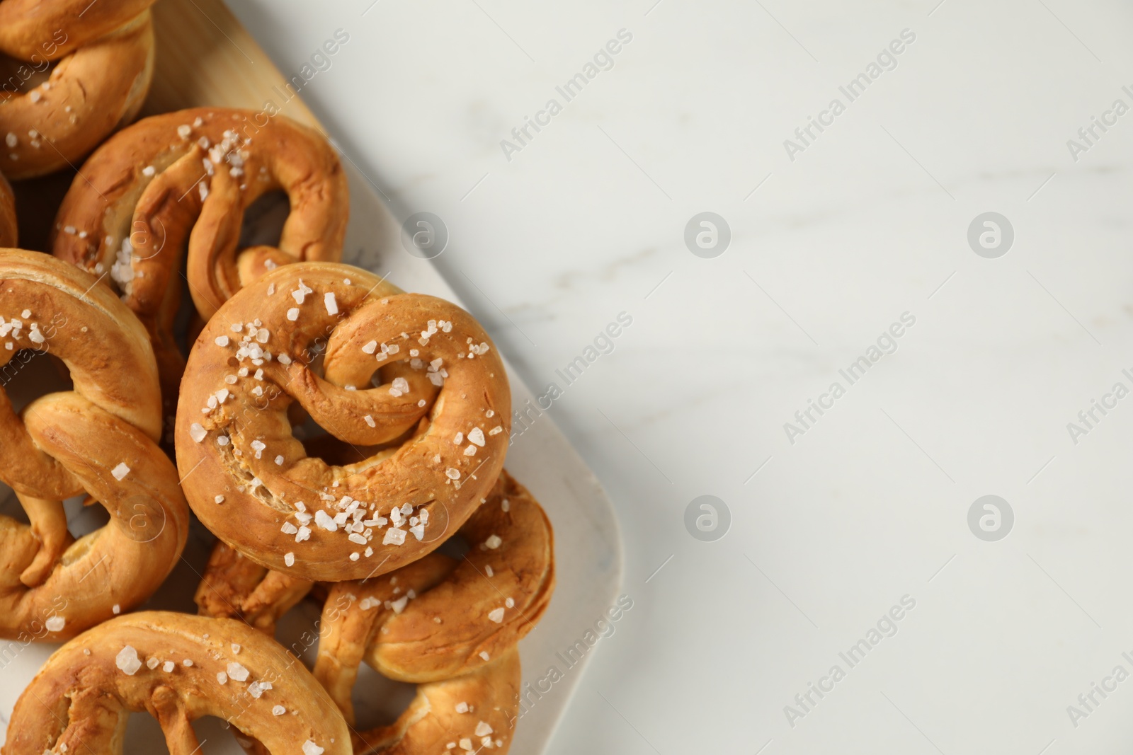 Tasty pretzels with salt on white marble table, flat lay. Space for text Photo of Tasty pretzels with salt on white marble table, flat lay. Space for text