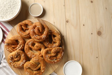 Photo of Tasty pretzels and ingredients on wooden table, flat lay. Space for text