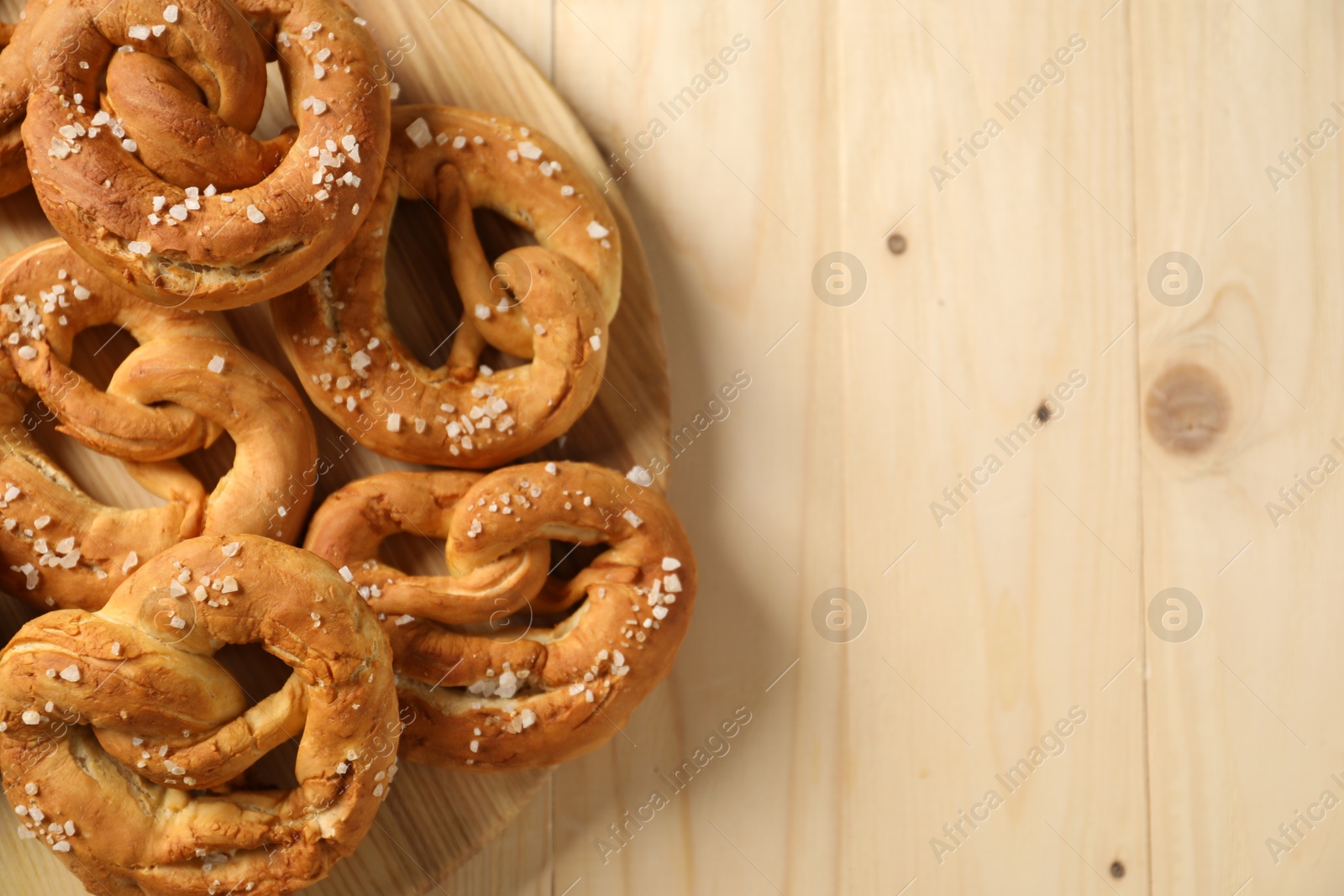 Tasty pretzels with salt on wooden table, top view. Space for text Photo of Tasty pretzels with salt on wooden table, top view. Space for text
