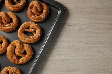 Photo of Tasty pretzels with salt on wooden table, top view. Space for text