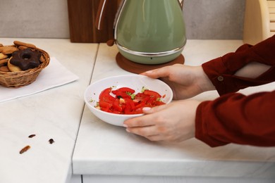 Photo of Woman holding bowl with vegetables and cockroaches in kitchen, closeup