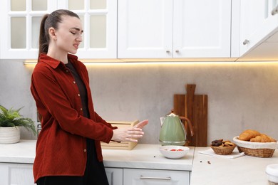 Photo of Emotional woman afraid of cockroaches in kitchen. Pest problem