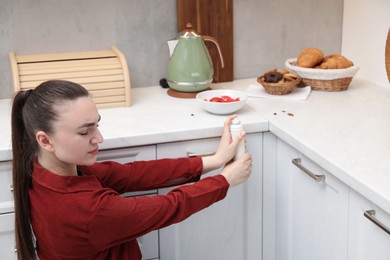 Photo of Woman spraying insecticide onto cockroaches in kitchen