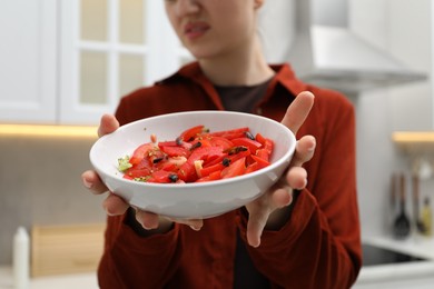 Photo of Woman holding bowl with vegetables and cockroaches in kitchen, closeup