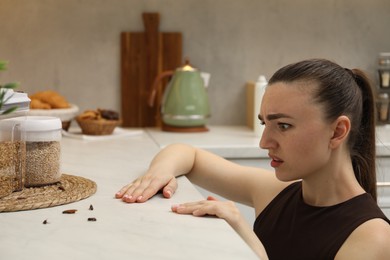 Photo of Woman looking at cockroaches on countertop in kitchen