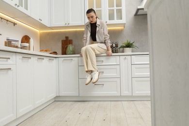 Photo of Emotional woman looking in disgust at cockroaches on floor indoors. Pest problem