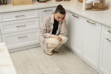 Photo of Emotional woman looking in disgust at cockroaches on floor indoors. Pest problem