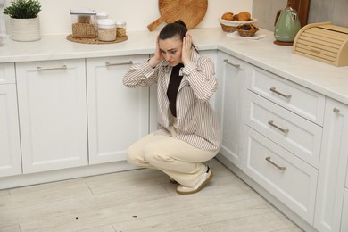 Photo of Emotional woman looking in disgust at cockroaches on floor indoors. Pest problem