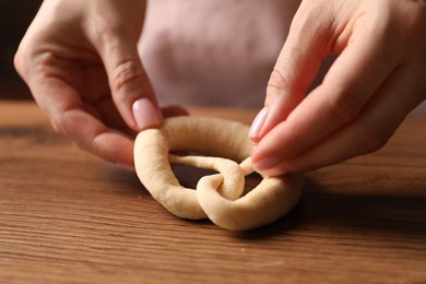 Photo of Woman shaping pretzels at wooden table, closeup