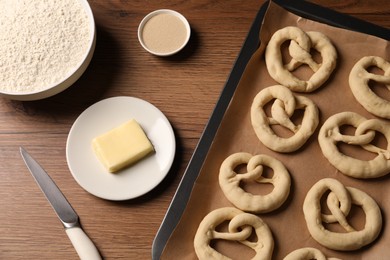 Photo of Uncooked pretzels and ingredients on wooden table, flat lay