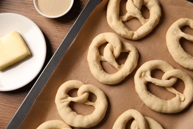 Photo of Uncooked pretzels and ingredients on wooden table, flat lay
