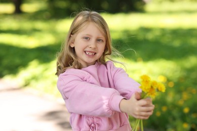 Photo of Cute little girl with beautiful dandelions in park