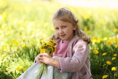 Photo of Cute little girl with beautiful dandelions outdoors on sunny day