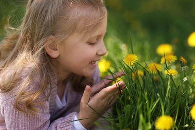 Photo of Cute little girl among beautiful dandelions outdoors on sunny day
