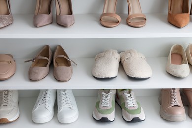 Photo of Different footwear on shelves indoors, closeup. Shoe storage