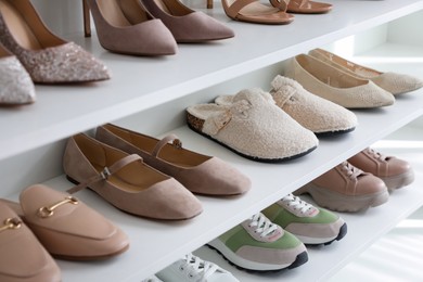Photo of Different footwear on shelves indoors, closeup. Shoe storage