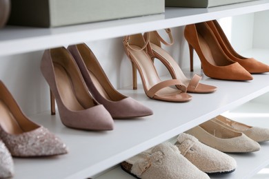 Photo of Different footwear on shelves indoors, closeup. Shoe storage