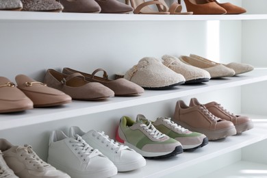 Photo of Different footwear on shelves indoors, closeup. Shoe storage