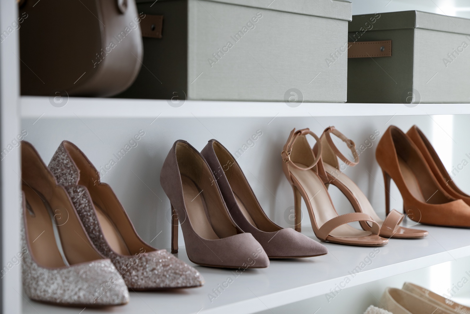 Photo of Different footwear on shelves indoors, closeup. Shoe storage