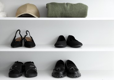 Photo of Different footwear and clothes on shelves indoors. Shoe storage