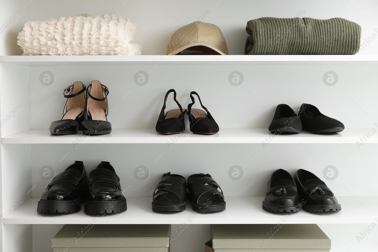Different footwear and clothes on shelves indoors. Shoe storage Photo of Different footwear and clothes on shelves indoors. Shoe storage
