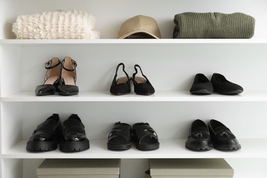 Photo of Different footwear and clothes on shelves indoors. Shoe storage