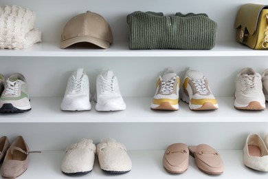 Photo of Different footwear, clothes and accessories on shelves indoors. Shoe storage