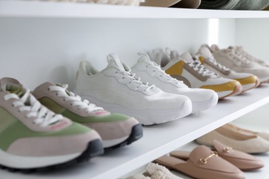 Photo of Different footwear on shelves indoors, closeup. Shoe storage