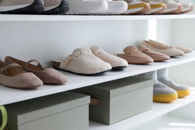 Photo of Different footwear on shelves indoors, closeup. Shoe storage