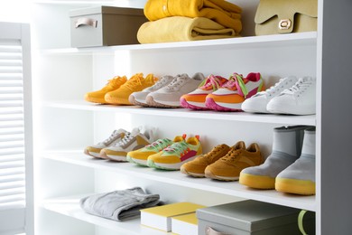 Photo of Different footwear, clothes and bag on shelves indoors, closeup. Shoe storage