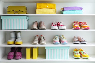 Photo of Different footwear, clothes and bag on shelves indoors. Shoe storage