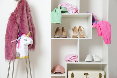 Photo of Shelving unit with different footwear, accessories and clothes indoors. Shoe storage