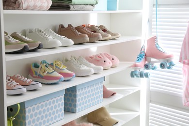 Photo of Different footwear and clothes on shelves indoors, closeup. Shoe storage