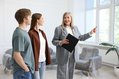 Photo of Smiling real estate agent working with couple at home