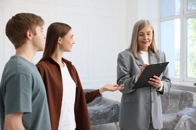 Photo of Smiling real estate agent working with couple at home