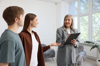 Photo of Smiling real estate agent working with couple at home
