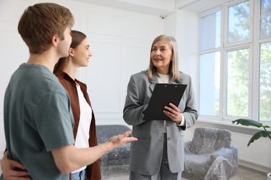 Photo of Smiling real estate agent working with couple at home