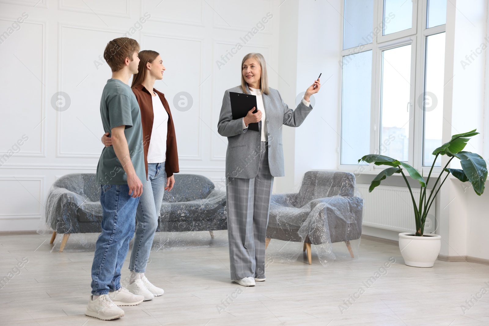 Smiling real estate agent showing apartment to couple indoors Photo of Smiling real estate agent showing apartment to couple indoors