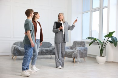 Photo of Smiling real estate agent showing apartment to couple indoors